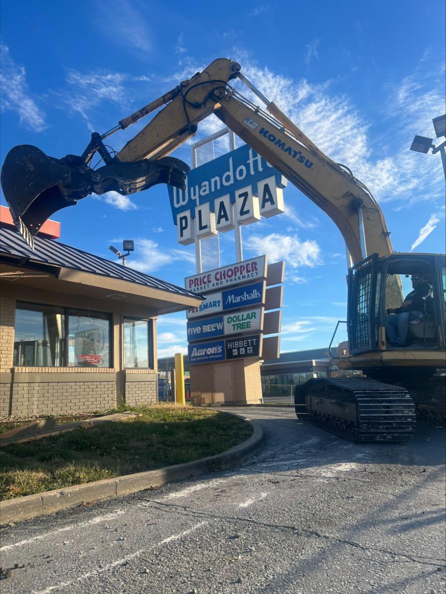 Excavator working near commercial plaza sign